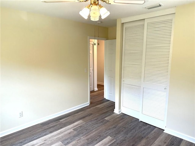 unfurnished bedroom featuring ceiling fan, dark wood-type flooring, and a closet