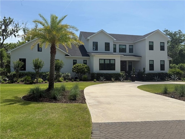 view of front of property with stucco siding, curved driveway, and a front lawn