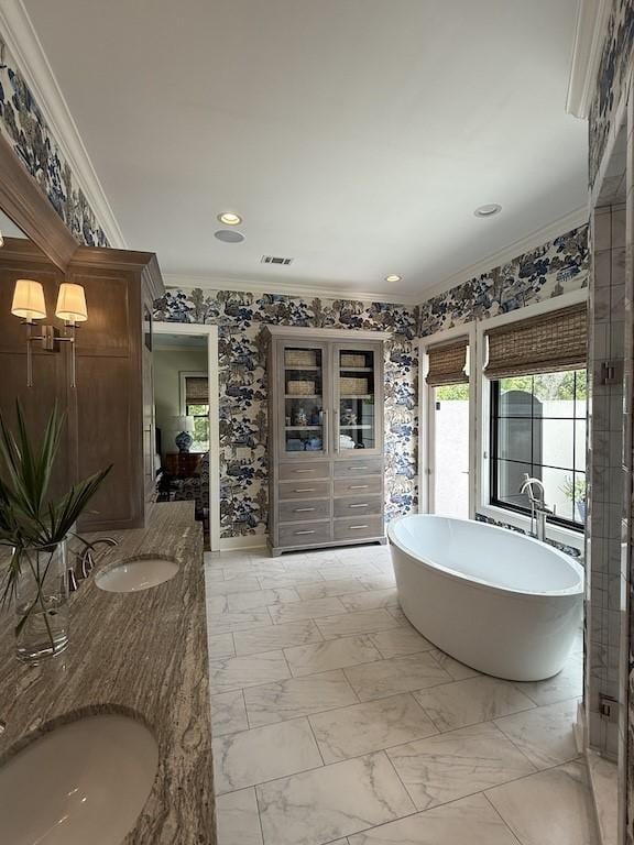 bathroom featuring ornamental molding, visible vents, a sink, a freestanding tub, and double vanity