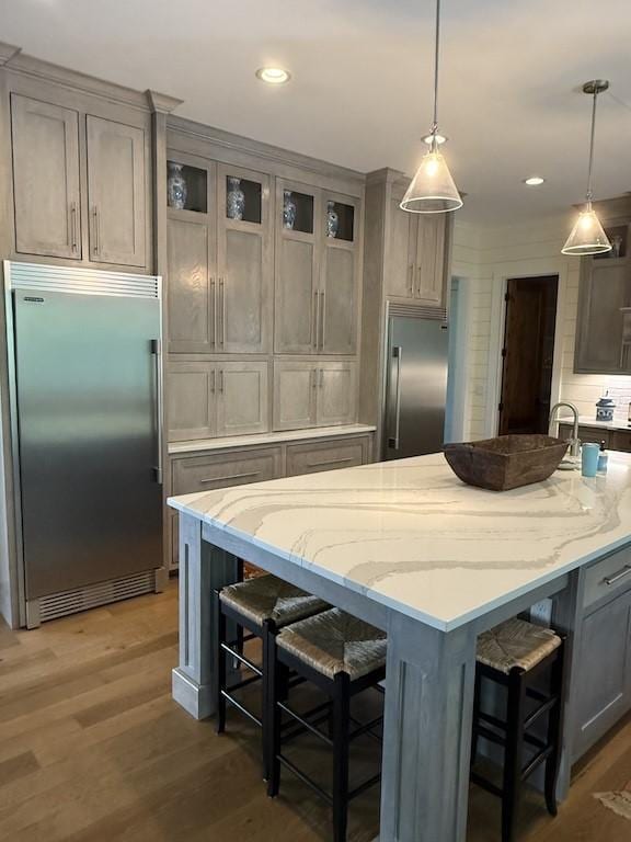 kitchen featuring light stone counters, built in fridge, and a breakfast bar