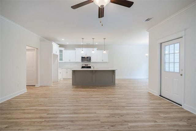 860 Kaitlyn Ave, Odum, GA 31555 - kitchen with appliances with stainless steel finishes, decorative light fixtures, a center island with sink, light hardwood / wood-style flooring, and white cabinetry