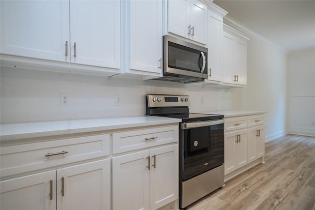 860 Kaitlyn Ave, Odum, GA 31555 - kitchen featuring light stone countertops, ornamental molding, light hardwood / wood-style floors, white cabinetry, and stainless steel appliances