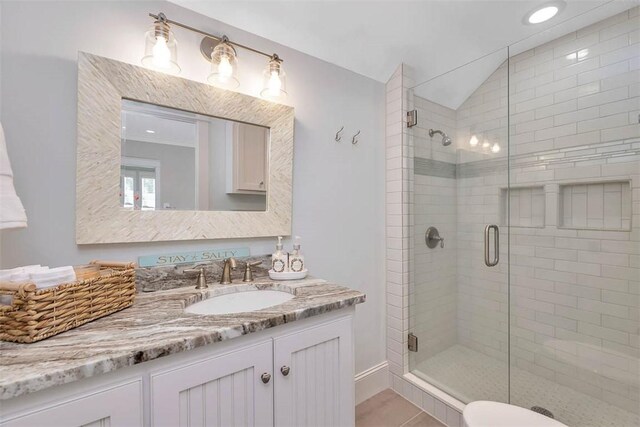full bathroom with a stall shower, vanity, baseboards, and vaulted ceiling