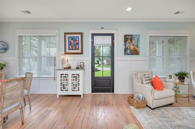 living area with a decorative wall, crown molding, a wainscoted wall, hardwood / wood-style flooring, and recessed lighting