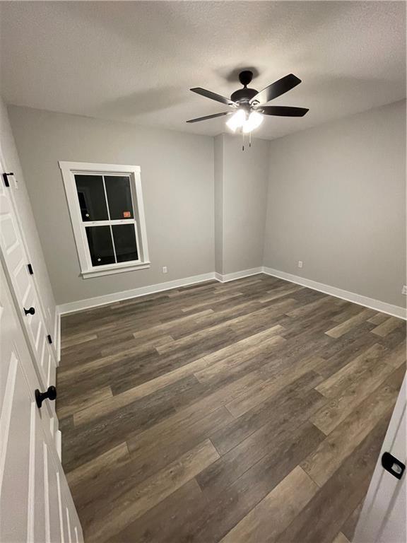 spare room with ceiling fan, dark hardwood / wood-style flooring, and a textured ceiling