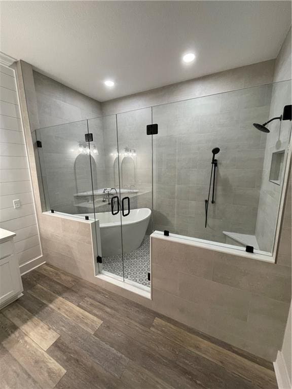 bathroom featuring hardwood / wood-style flooring, vanity, and plus walk in shower