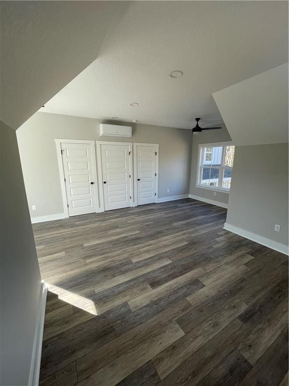 bonus room with ceiling fan, dark hardwood / wood-style floors, and a wall unit AC