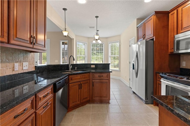 kitchen with appliances with stainless steel finishes, tasteful backsplash, sink, light tile patterned floors, and decorative light fixtures