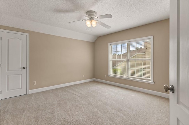 empty room with vaulted ceiling, ceiling fan, light carpet, and a textured ceiling