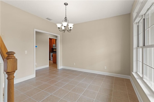 empty room with light tile patterned floors and a notable chandelier