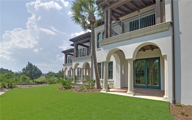 back of property with a balcony and a yard