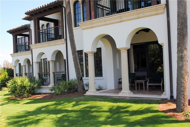 rear view of property with a balcony and a yard