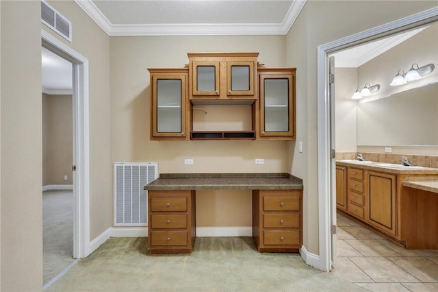 unfurnished office featuring ornamental molding, built in desk, and light colored carpet