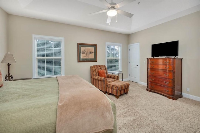 carpeted bedroom with ceiling fan and a tray ceiling