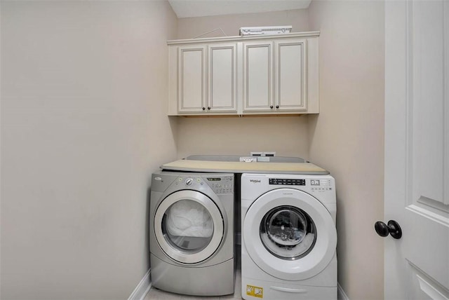 clothes washing area with cabinets and washer and clothes dryer