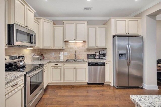 kitchen featuring stainless steel appliances, cream cabinets, sink, and dark hardwood / wood-style flooring