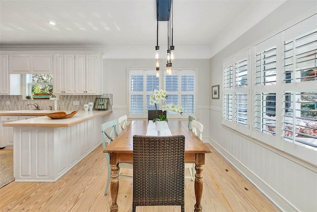 dining space featuring a wainscoted wall and light wood-style floors