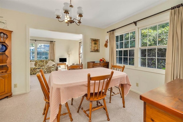 dining space featuring light colored carpet and a chandelier