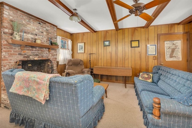 carpeted living room featuring ceiling fan, beam ceiling, wooden walls, and a brick fireplace