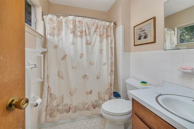 full bathroom with tile patterned floors, toilet, shower / tub combo with curtain, vanity, and tile walls