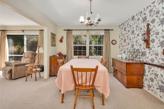 dining space featuring light carpet and an inviting chandelier