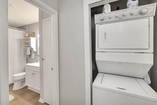 washroom featuring light hardwood / wood-style floors and stacked washer and dryer