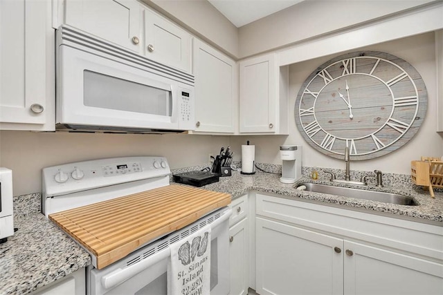 kitchen with light stone countertops, sink, white cabinets, and white appliances