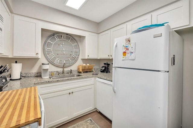 kitchen with white cabinets, light stone countertops, white appliances, and sink