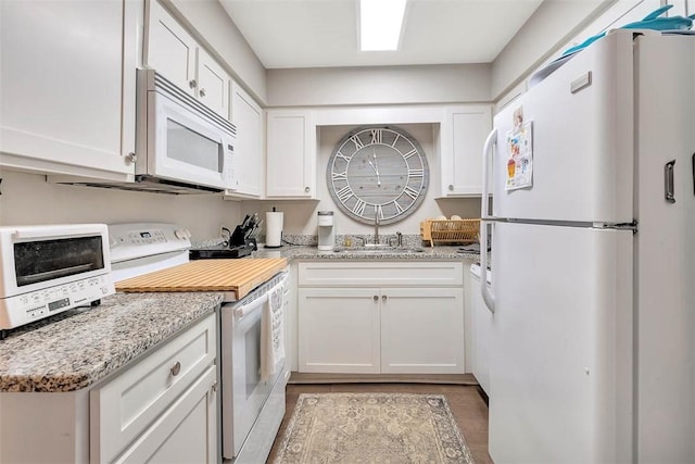 kitchen featuring white cabinetry, sink, light stone counters, and white appliances