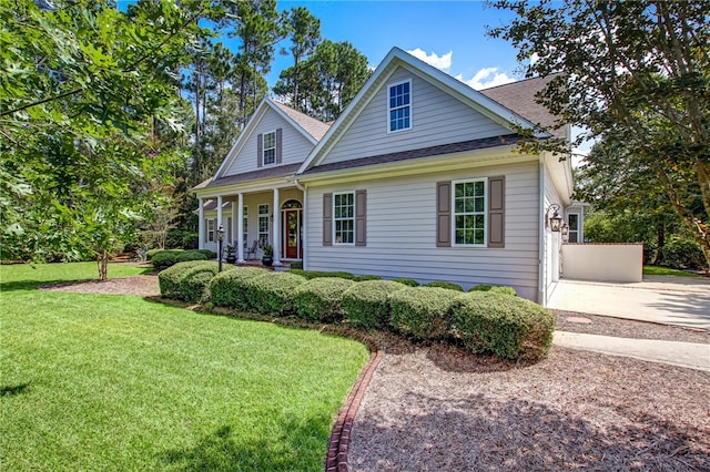 view of front of home with covered porch, driveway, a front lawn, and roof with shingles