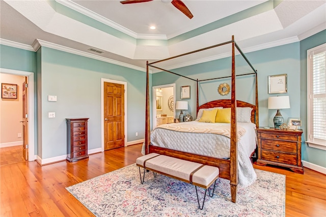 bedroom with a raised ceiling, visible vents, and crown molding