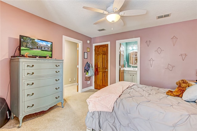 bedroom featuring light colored carpet, visible vents, connected bathroom, and a textured ceiling