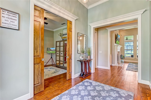 foyer entrance with ornamental molding, baseboards, a fireplace, and hardwood / wood-style floors