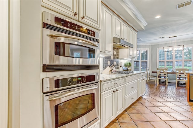 kitchen with light tile patterned flooring, under cabinet range hood, visible vents, appliances with stainless steel finishes, and crown molding