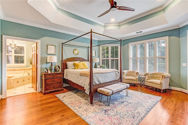 bedroom featuring ornamental molding, a tray ceiling, visible vents, and light wood finished floors