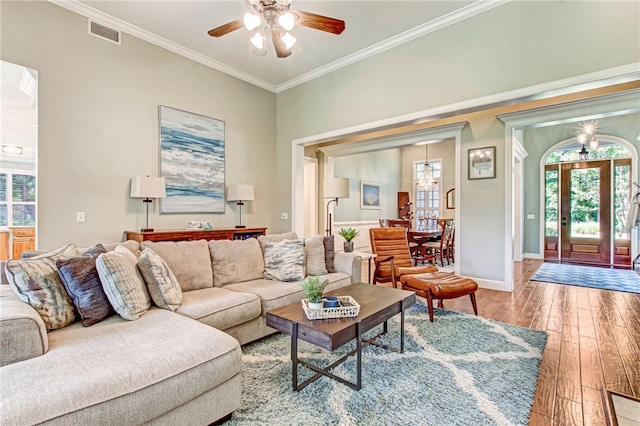 living area featuring baseboards, visible vents, a ceiling fan, hardwood / wood-style flooring, and ornamental molding