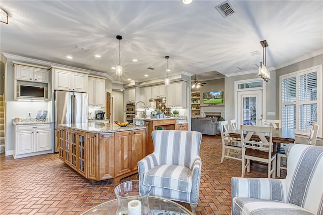 kitchen with brick floor, a spacious island, visible vents, ornamental molding, and appliances with stainless steel finishes