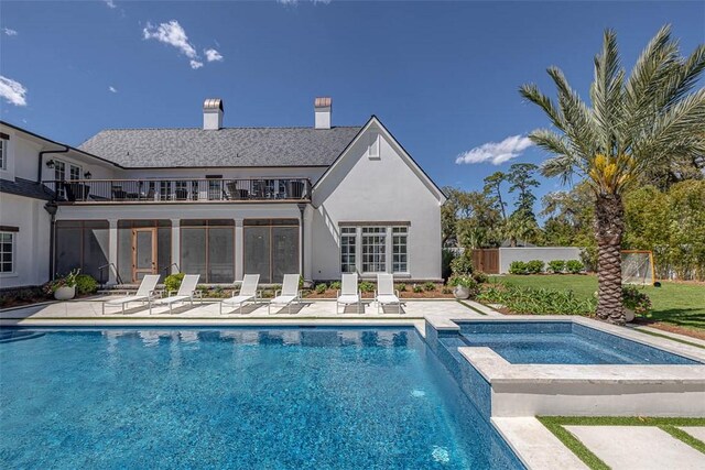 back of house with a balcony, a patio, and a pool with hot tub