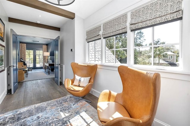 sitting room with beamed ceiling and wood-type flooring