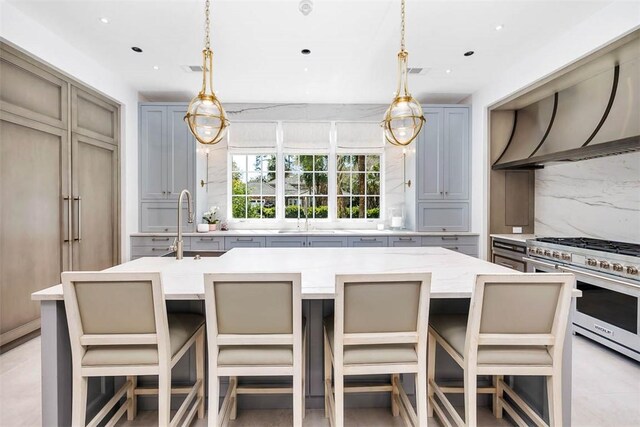 kitchen with backsplash, stainless steel stove, a breakfast bar area, and gray cabinetry