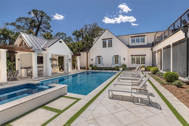 view of pool with an in ground hot tub, a patio, and exterior kitchen