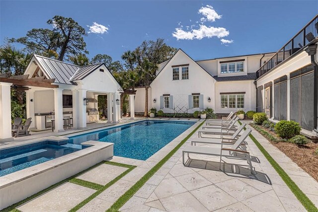 view of pool with an in ground hot tub, a patio, and exterior kitchen