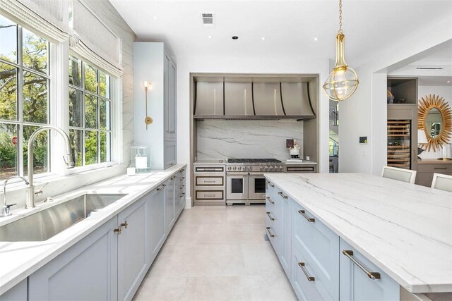 kitchen with backsplash, range with two ovens, sink, and a wealth of natural light