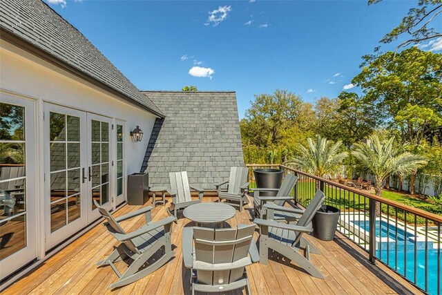 wooden deck featuring a fenced in pool and french doors