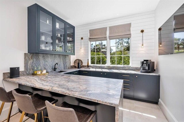 bar with tasteful backsplash, plenty of natural light, hanging light fixtures, and sink