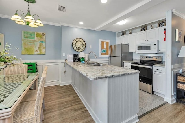 1175 N Beachview Dr Unit 279, Jekyll Island, GA 31527 - kitchen with appliances with stainless steel finishes, a sink, white cabinets, a peninsula, and light wood-style floors