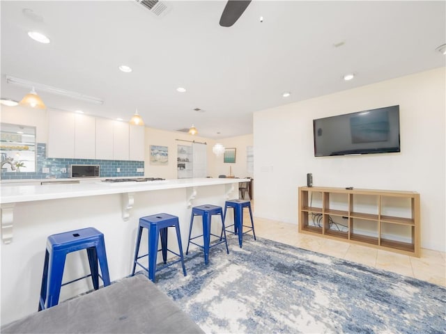 900 Mallory St, Saint Simons Island, GA 31522 - kitchen featuring white cabinets, a kitchen breakfast bar, gas cooktop, light countertops, and ceiling fan