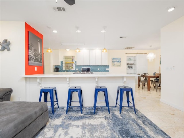 900 Mallory St, Saint Simons Island, GA 31522 - kitchen with decorative backsplash, a breakfast bar, pendant lighting, light countertops, and recessed lighting