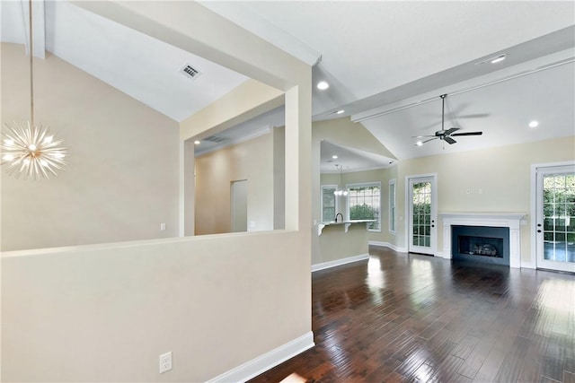 unfurnished living room with lofted ceiling with beams, plenty of natural light, dark wood-type flooring, and ceiling fan with notable chandelier