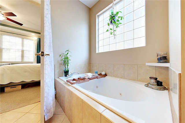 bathroom with tile patterned floors, ceiling fan, a relaxing tiled tub, and a healthy amount of sunlight